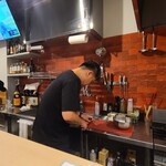 小皿ダイニング POND - 店内は剥き出しの天井、コンクリートの壁、コンクリート床、厨房側は赤い煉瓦調タイル貼り壁、オープンキッチンでカジュアルな雰囲気、BGMは洋楽
お席はカウンター10席、テーブル8席×1卓の合計18席
