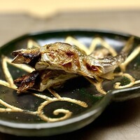 徳ㇵ本也 - ❻稚鮎の塩焼き
                    〜琵琶湖産の稚鮎を窯でじっくり塩焼きに。串を縦に刺して焼くことによって、熱が滞留せずに均等にふっくらと熱が入る。余分な水分を飛ばし旨味を凝縮させる日本古来の"原始焼き"だな。