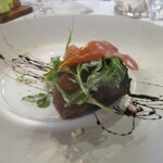 Une Fleur - フォアグラと黒無花果：カリフォルニア黒無花果を 赤ワインとスパイスで煮込んで最下層に敷き、スライスしたブリオッシュ（やわらかなパン）を置き、フランス産の最高級フォアグラがのせてあります。うえには、生ハムとセルバチコ（ルッコラの仲間）を飾り、白い陶磁のプレートはバルサミコソースで彩られています。