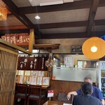 別館山田 - 入り口入ってすぐ右手のテーブル3個の真ん中の席から。のれんの右、スモークガラスの向こうに大将が焼いてらっしゃる。お身体に気をつけてください。