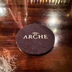 バー　アルシェ - 木目のカウンターに置かれているコースター