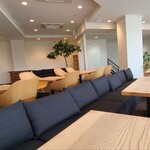 Cafe ふふふあん - 白い天井、白壁&ガラス張り壁、カーペットタイル貼り床、観葉植物があり、お席の間隔はゆったり、のんびりと寛げる雰囲気
お席はガラス張り壁カウンター8席、テーブル4席×9卓、テーブル2席×6卓の合計56席