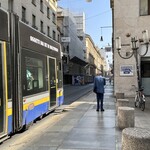 Starbucks - トラムの横を歩く年配の男性。このようにハンガーに架かっようなジャケットの着方をするイタリア人は多い。