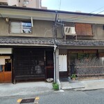 鮨 三心 - 外観は町屋造り長屋の古民家の1階にあり、漆喰壁&木板張り壁、枯れ枝の垣があり、侘び寂びを感じさせる趣きのある佇まい
      またお店の横には待合室兼喫茶室があり、入店待ち&食後のデザートを頂く様になっています