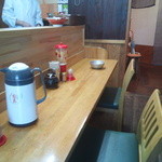 来来 - L字ｶｳﾝﾀｰと、奥にﾃｰﾌﾞﾙ席があり。卓上には炒り粒ｺﾞﾏ、粗挽きｺﾞﾏ、ｺｼｮｳ、一味。