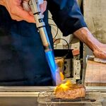 鉄板焼きWAGYU LIVERARY - 最高級黒毛和牛ステーキをバーナーで焼いているところ(最高級黒毛和牛スタンダードコース)