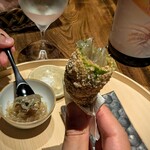 温石 - ご一緒様の実演。芳ばしくオカキ衣で揚げられた、熱々の甘長唐辛子の空洞に、冷たい生シラスの漬けを詰めながら齧る一品は、遊び心と美味しさが共存していて見事！！