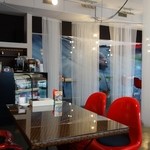 De PLUS CAFE - レースのカーテン（仕切）越しに、童夢-零（ドウム・ゼロ）の写真が少し見えます。