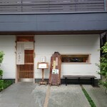 佳肴 三佐和 - 店舗外観 (開店前)。すっきりとした佇まい。長椅子の上の窓からは、清潔感に満ちた店内の様子が窺える。