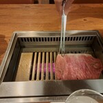 焼肉うしごろ - 群馬県産の大判サーロインを、網の鉄板で焼いている様子のその1です。