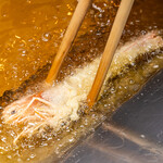 天ぷらスタンド 北吉 - 天ぷらを揚げている写真