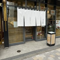 おつな寿司 - ガラス張りの内側の和モダン内装と白い暖簾が目を引く店構え