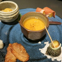 凛と - お通しは鯛の茶わん蒸し、ほたてひものぬた、キウイ生ハム、鴨のショウガ焼き、姫サザエ。