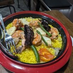 ナカガワ☆スエ食堂 - パエリア（真中にある黒い食材が、そのまま食べても辛くないスペインの唐辛子です。）
