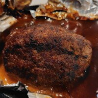 びふてき洋食存じやす - アルミの包を開けると焦げがついた冷めたハンバーグ。ハンバーグを割ってもメニューのようなチーズはなし。