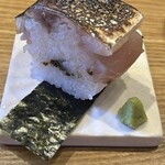 食堂Light - お通しは鯖の棒鮨  鯖の表面を香ばしく炙っていて中はレア。お米の硬さも丁度良く、昆布の佃煮が中に詰められている。