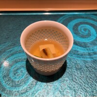 札幌 鮨 よこ田 - 最初は椀？から。昆布出汁の汁物です。具は豆腐、焼いた長ネギ、インゲンなど。底に沈んでるのは何だろう？海老芋？ちょっと分かりませんでした。