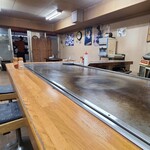 曽江井お好み焼店 - 店内はクリーム色の天井、麒麟ビールのポスターが貼られたクリーム色の壁&ガラス張り壁&漫画の本棚、ベージュ色のタイル貼り床、ゆったりとした空間
BGM代わりのテレビ音声が流れています