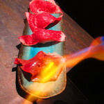 しなもん堂 - 道産和牛ブリスケの炙り肉寿司４貫　２２９９円（税込）をバーナーで炙り中　2【２０２５年１月】