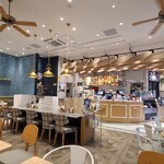 フレッシュネスバーガー - 店内は大きな天井吊り扇風機が下がった白い天井、ターコイズブルーのタイル貼り壁&大きな鏡が貼られた白壁&ガラス張り壁、ナチュラルカラーの木板パネル張り床、街中ながらリゾート感のある雰囲気、BGMは洋楽