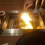 焼肉うしごろ - 鹿児島県産の大判サーロインを、網の鉄板で焼く様子のその1です。見事なファイヤーダンスを演出しています。