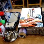 磯丸水産 - テーブルの標準のセッティングです。焼き網の上に乗っかっているのがランチのメニューです。