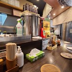 鍋焼らうめん ひさし - ダークグレーの天井、ビールのポスター等が貼られたライトグレーの壁、焦茶色の木板張り床、コンパクトな空間、BGMはJ-POP
            カウンター10席、テーブル6席×1卓、テーブル2席×1卓の合計18席