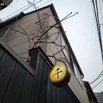 神楽坂 和食 千 - 塀の中に立つ木のオブジェから外に伸びた枝の先に、花梨を表しているのだろうか、“千” の文字が入った黄色い実が成っている。