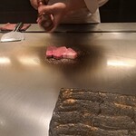 日比谷 モンシェルトントン - 鉄板の上の熊本県産の和王のサーロインに、胡椒をふる様子です。