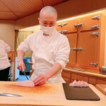 鮨 しゅん輔 - 真鯛を斬り付ける高岡氏。花粉除けのマスク姿です