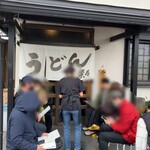 手造りうどん 楽々 - お店の入口　時間前にお品書きが配られます。
