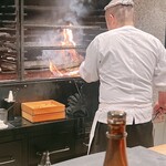 薪鳥新神戸 - 薪場の前で網に入れたウルイと菜の花をザクッ、ザクッと炙ります