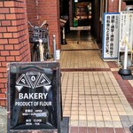 ポフベーカリー - 入口に黒い看板。ビルの奥に緑色の店舗があります。