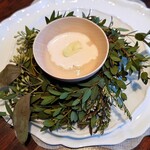 Florilege - グリーンのリースに囲まれたタマネギのスープのプレゼンテーション。タマネギの甘さとフキノトウの軽い苦みの組み合わせ。