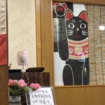 西むら - 正面ののれんの上に、こんな招き猫(猫の鈴が目より大きいかわいい)