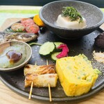 Tea Break .m - 時計周りで上から　お豆腐、あんこ、きな粉、ゴマ、厚焼き卵、竹輪、刺身こんにゃく、イワシの生姜焼き、トマト、カボチャの煮付け　