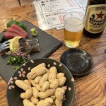 赤羽金太郎 - 赤星、お通しの落花生、刺身三点盛り（しめ鯖、まぐろ赤身、イワシの炙り）。