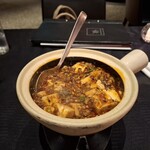 スーツァン・レストラン陳 - 土鍋に入れた四川飯店伝統の麻婆豆腐を、かき混ぜながら火で温めている様子です。