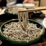 よしじ - 箸でリフトすると麺がしっかり長い！唇に当たる表面のザラつきは挽きぐるみならではのもの。蕎麦の野趣溢れる生々しい蕎麦の香りが鼻に抜けていきます。
