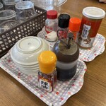 まるよし - 卓上の調味料（塩、激辛一味スパイス、一味唐辛子、胡椒、餃子のタレ、ラー油）