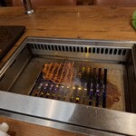 焼肉うしごろ - 赤いタレに漬け込んだ大分県産の特選サーロインを、網の鉄板の上で焼いている様子のその2です。