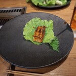 焼肉うしごろ - 赤いタレに漬け込んだ大分県産の特選サーロインを、網の鉄板で焼いた後サンチュ、大葉、葉唐辛子、アスパラガスのピクルスの上にのせた様子のその1です。