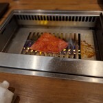 焼肉うしごろ - 赤いタレに漬け込んだ大分県産の特選サーロインを、網の鉄板の上で焼いている様子のその6です。