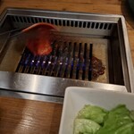焼肉うしごろ - 赤いタレに漬け込んだ大分県産の特選サーロインを、網の鉄板の上で焼いている様子のその3です。