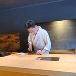 鮨 三心 - 墨色の天井にはダウンライトを配置した木板が吊り下げられ、白木のL字カウンターがアクセントにはなっていますが、墨色の壁と墨色の床、水墨画の世界に迷い込み、お料理のみが鮮やかな色を纏った様な世界観