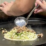 鉄板焼 OMURAYA - そのぼっかけを穴あきお玉で掬って乗せます。