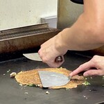 鉄板焼 OMURAYA - テコで強めに押さえて薄く焼き上げます。