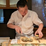 新日本料理おぶね - 蒸しあがったばかりで熱々の鮑を手際よく調理する大将。