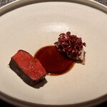 アニエルドール - レアに焼き上げられた宮崎牛は、柔らかく口中で溶けていくよう。添えられたトレヴィスの中には八尾産の枝豆と牛リエット。どこか懐かしい味とモダンな調理技法が交差する、不思議な懐かしさがあります。中央には京都の大徳寺納豆を使った黒いオイルがあり、その深い発酵の香りが肉の脂と溶け合います。