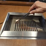 焼肉うしごろ - 店長が、網の鉄板に牛脂を塗る様子です。